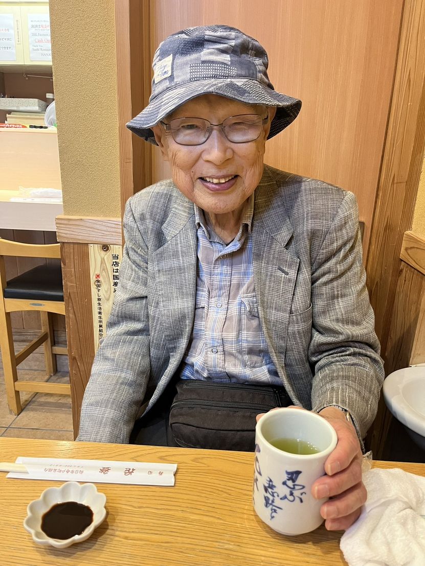 帽子とジャケット姿で笑顔を見せる代表の小野孝治